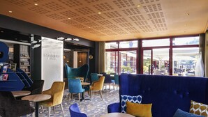 A modern interior with seating areas, a reception desk, and a view of the outside. - Mercure Dinan Port Le Jerzual (Lanvallay)