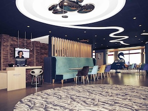 Un hall d’hôtel moderne doté d’un comptoir d’accueil, d’un espace salon et d’un design de plafond original.