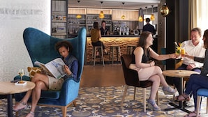 A modern bar area with a bar counter, seating, and a decorative wall with a shark motif. - Mercure Dinan Port Le Jerzual (Lanvallay)
