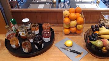 A breakfast spread with various jams, oranges, and a fruit basket.