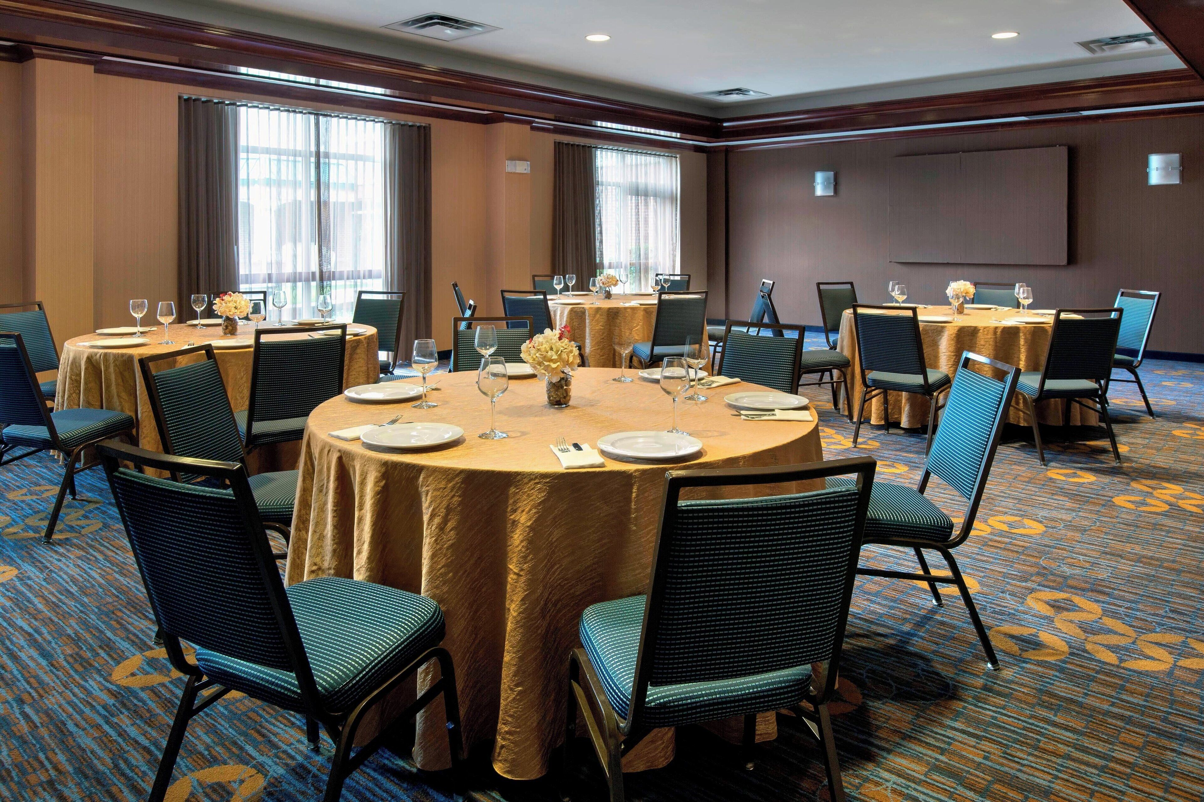 Une salle de conférence équipée de tables rondes, de chaises et d’un grand écran.