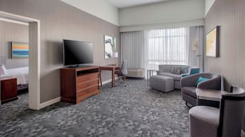 Una habitación de hotel con una cama, un escritorio con televisor, un sofá y una silla.