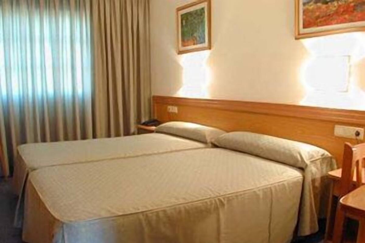 Una cama doble con cabecera de madera, una mesita de noche y una silla.