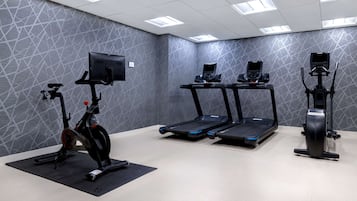 Un gimnasio con bicicletas estáticas, cintas de correr y una máquina de remo.