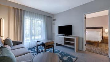 A hotel room with a sofa, a TV, a desk, and a bed.