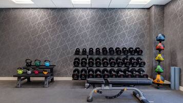 Un gimnasio con pesas rusas, mancuernas y una banca.