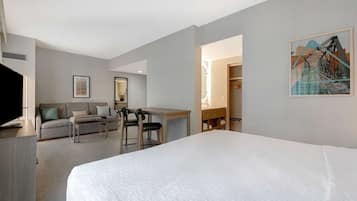 Ett hotellrum med en stor säng, ett skrivbord, en stol, en soffa och en garderob.
