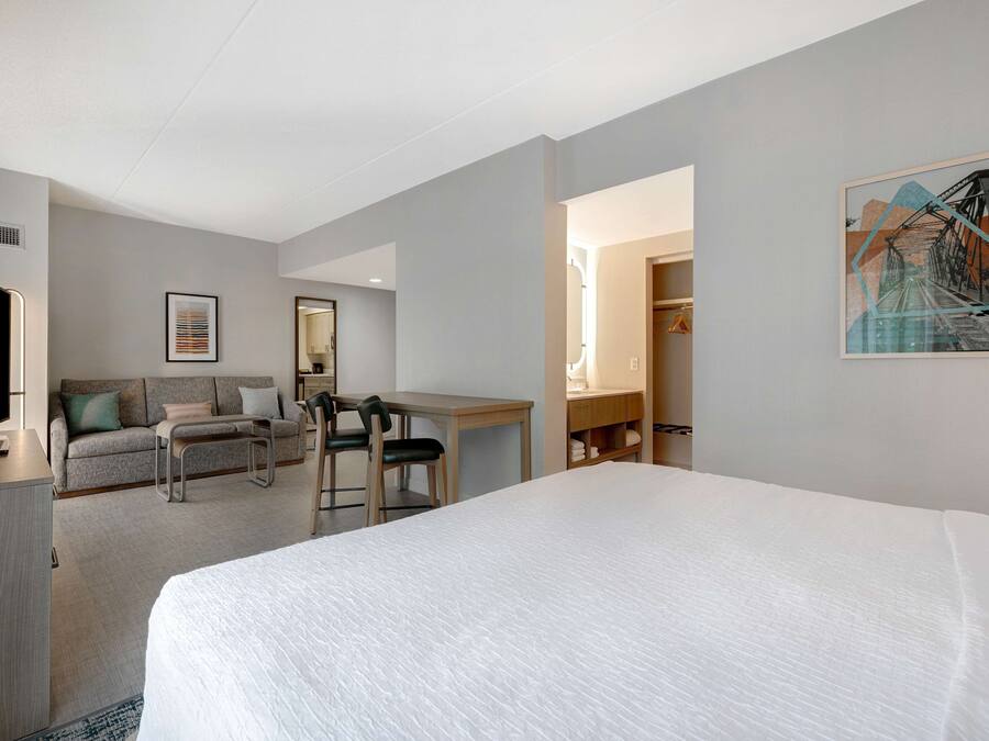 Ein Hotelzimmer mit einem großen Bett, einem Schreibtisch, einem Stuhl, einer Couch und einem Kleiderschrank.