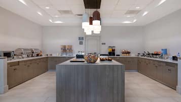 A modern kitchen with a central island, built-in appliances, and a variety of food items displayed on the countertops.
