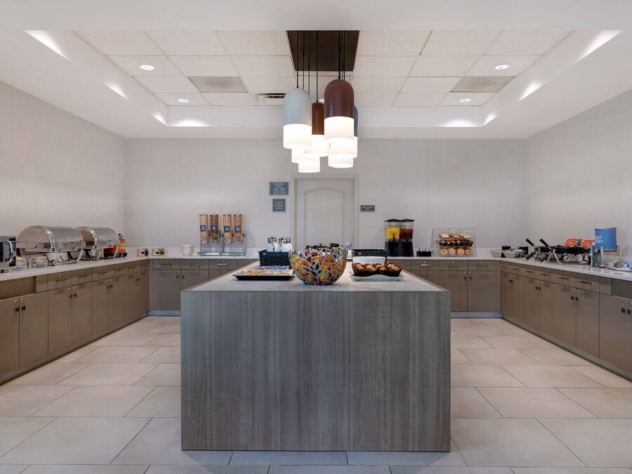 A modern kitchen with a central island, built-in appliances, and a variety of food items displayed on the countertops.