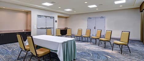 A conference room with a table, chairs, carpeted floor, and ceiling lights.