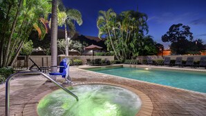 A pool area with a hot tub, lounge chairs, and palm trees. - Hilton Garden Inn Ft Myers (Fort Myers)