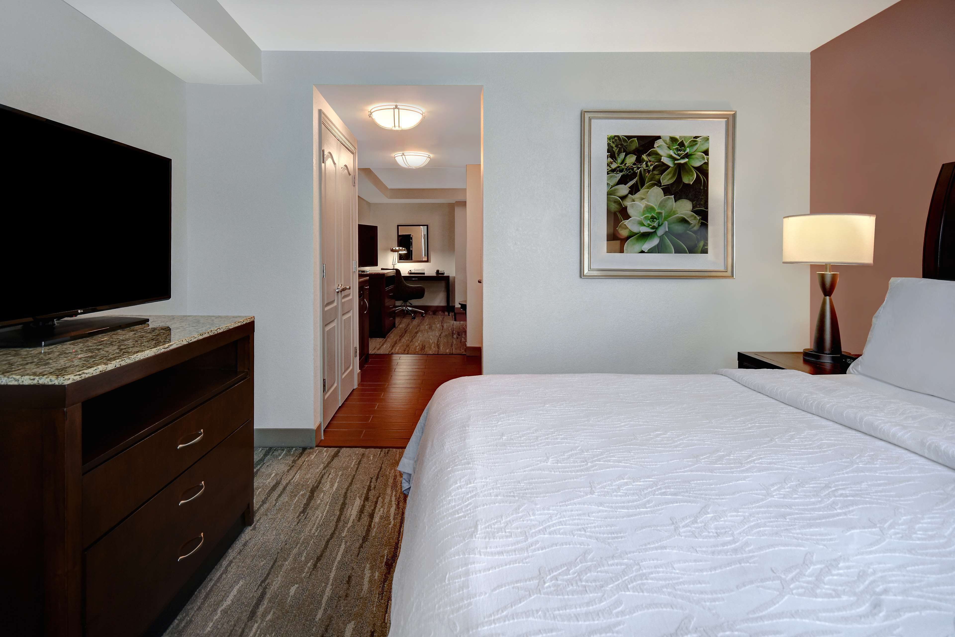 Ein Hotelzimmer mit Bett, Fernseher, Schreibtisch und sichtbarem Badezimmer hinter einer offenen Tür.