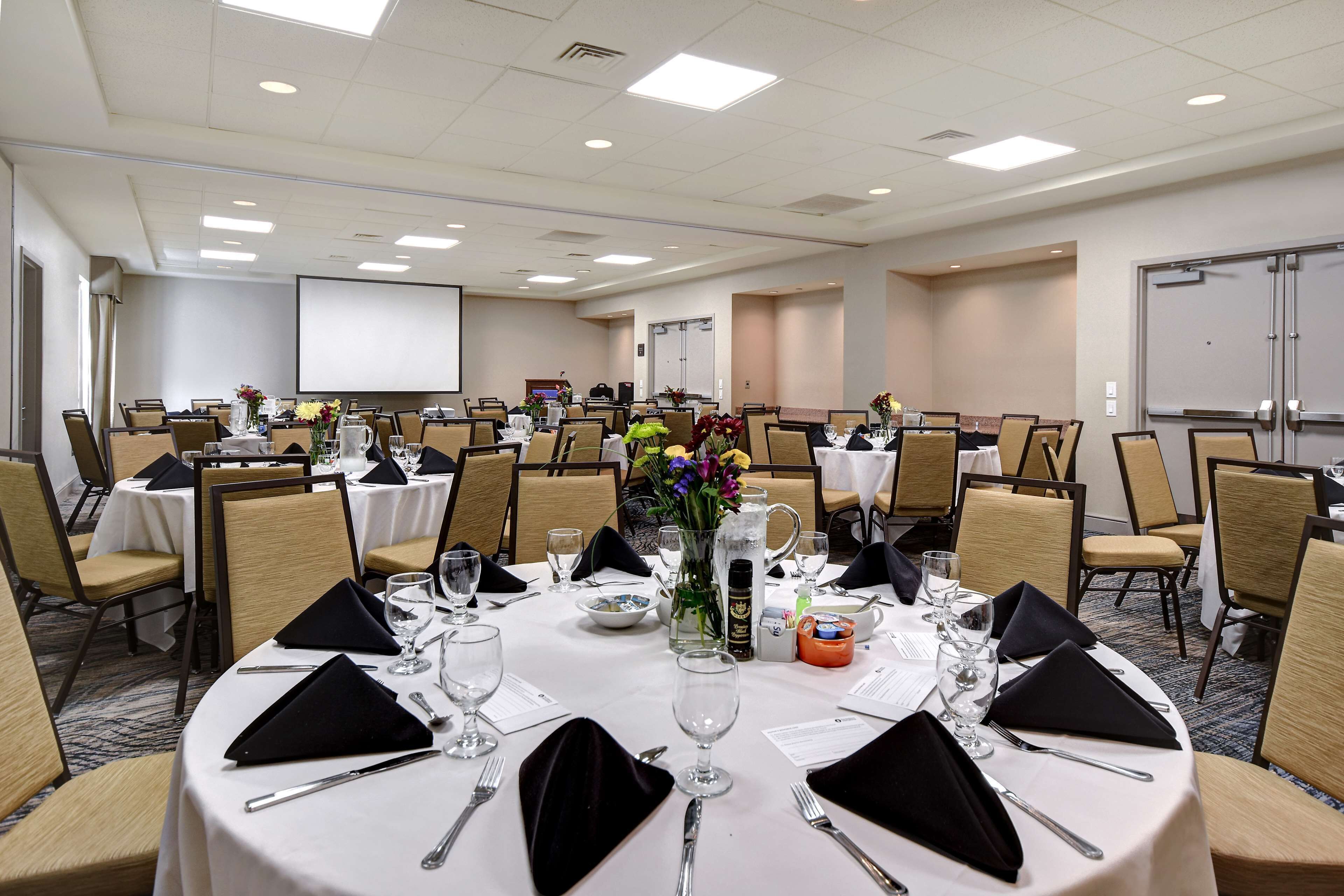 A conference room with round tables, chairs, and a projector screen.