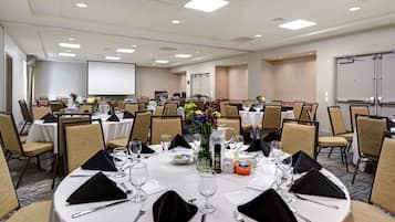 A conference room with round tables, chairs, and a projector screen.