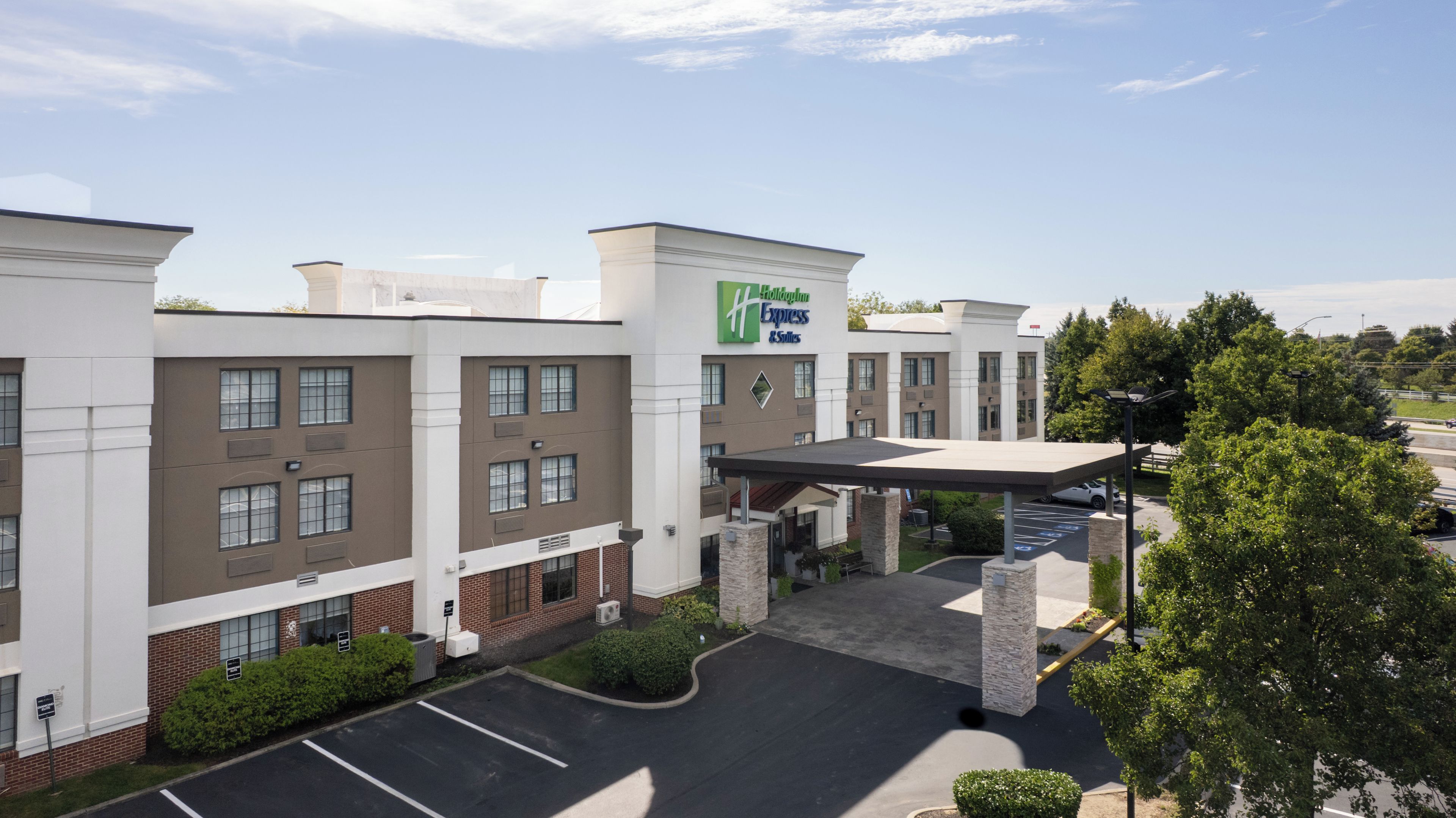 A hotel with a modern facade, a covered entrance, and a parking lot.