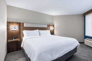 A hotel room with a large bed, a wooden headboard, bedside tables, and wall-mounted lighting. - Holiday Inn Express Hotel & Suites Columbus SW-Grove City by IHG (Grove City)