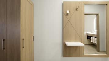 Un baño con un armario de madera, un espejo con repisa y un perchero para toallas.