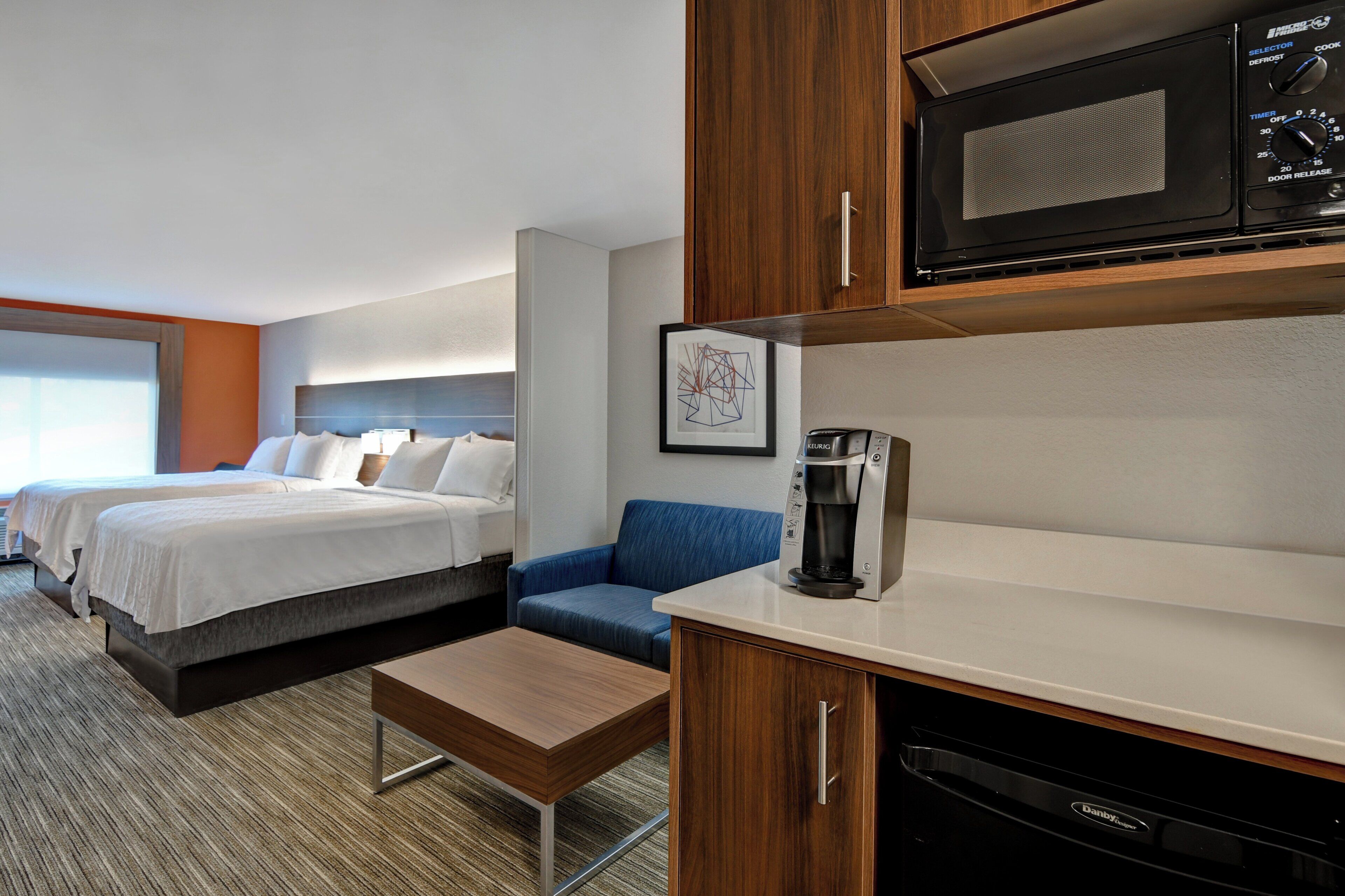 Een hotelkamer met een bed, een bureau, een koffiezetapparaat en een magnetron.