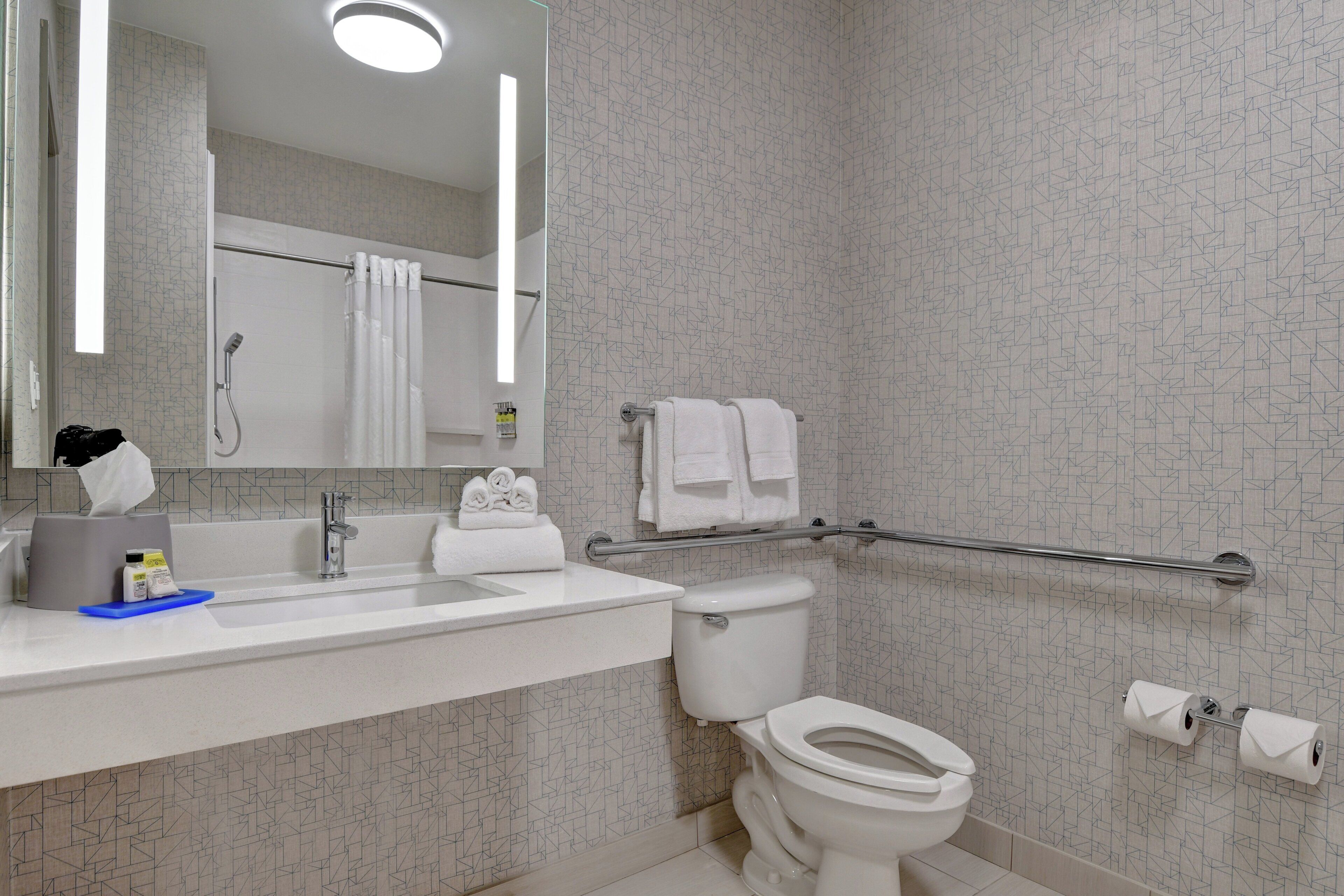 A modern bathroom with a white sink, mirror, and toilet.