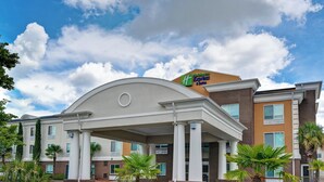 Un hotel Holiday Inn Express & Suites con un diseño arquitectónico moderno, que presenta una entrada destacada con columnas y un techo plano.