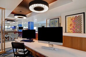 Un espacio de oficina moderno con múltiples estaciones de trabajo por computadora, una zona de recepción y un comedor.