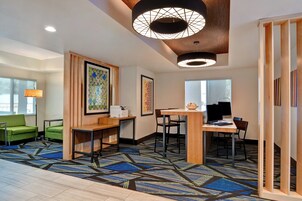 A hotel lobby with a reception desk, seating area, and artwork on the walls.