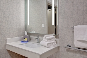 Une salle de bain avec un lavabo blanc, un miroir et un porte-serviettes.
