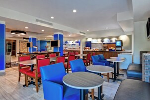 Un restaurante moderno con asientos rojos y azules, una panadería y una barra de frutas.