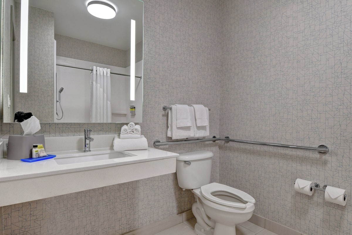 A modern bathroom with a white sink, mirror, and toilet.