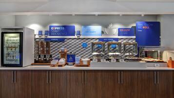 A breakfast buffet area with cereal, hot food, and a Quaker Oatmeal dispenser.