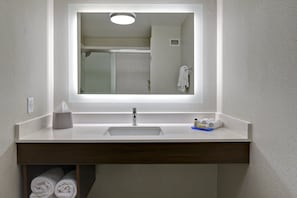 Une salle de bain avec un lavabo blanc, un miroir et un porte-serviettes.
