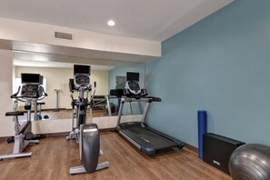 Ein Fitnessstudio mit Trainingsgeräten, darunter Laufbänder, ein Crosstrainer und ein Ergometer.