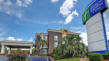 A Holiday Inn Express & Suites hotel with a clear sky, a parking lot, and well-maintained landscaping.