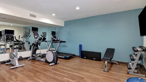 Un gimnasio con equipo de ejercicio, un espejo y una pared azul.