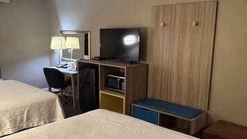 A hotel room with two beds, a desk with a computer, a television, a microwave, and a wardrobe.