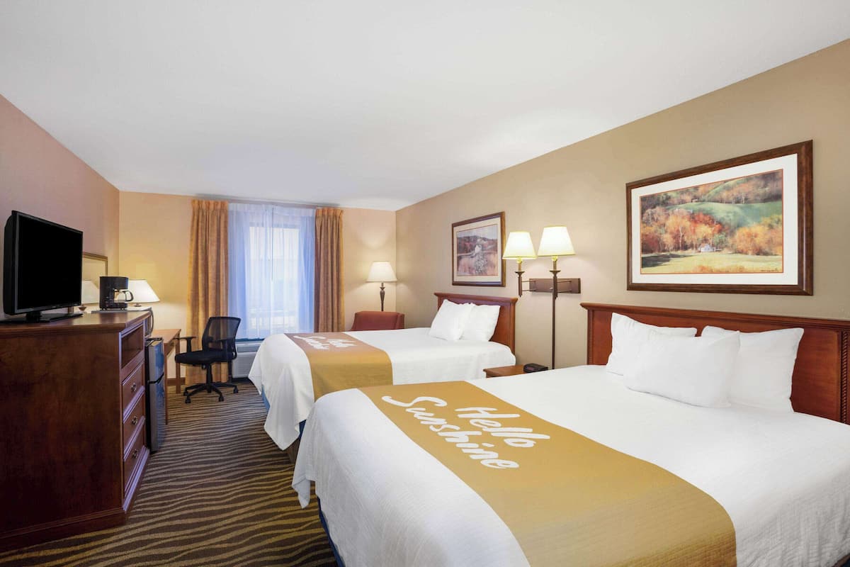Ein Hotelzimmer mit zwei Betten, einem Schreibtisch mit Fernseher und einem Sessel.