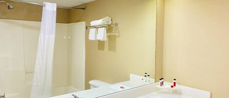 A bathroom with a large mirror, a sink, a shower, and a toilet.