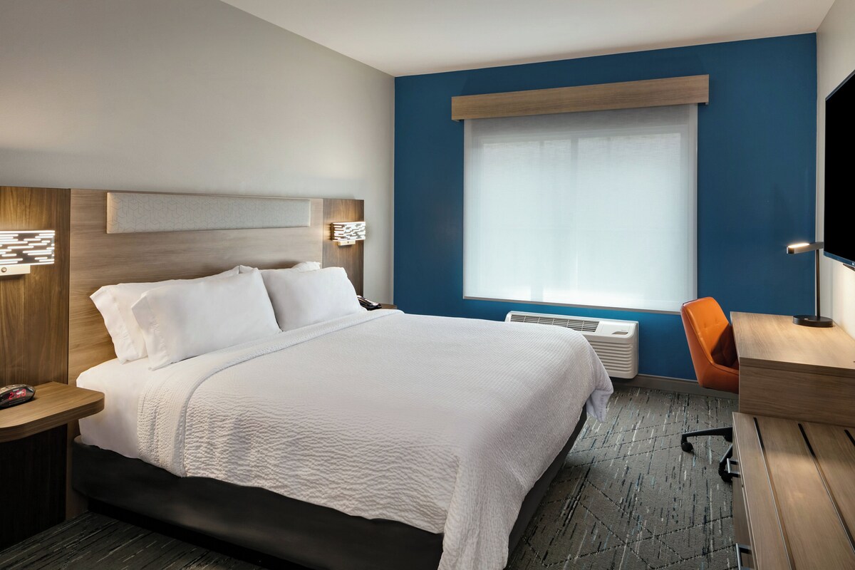 Une chambre d’hôtel avec un lit, un bureau et une chaise.