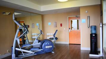Un gimnasio con equipamiento de ejercicio, dispensador de agua y un espejo.