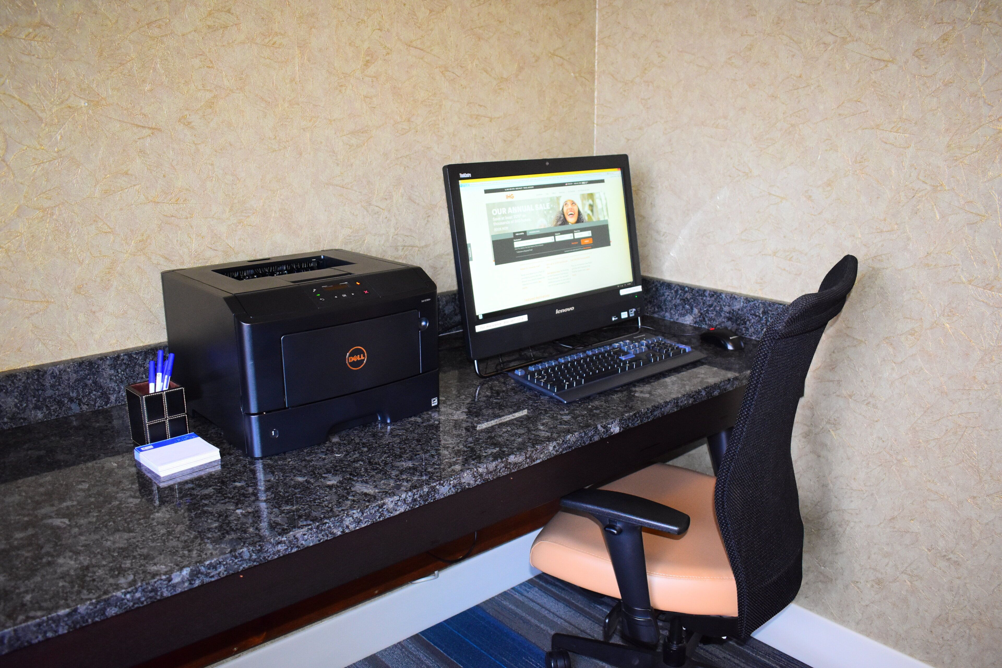 A desktop computer with a monitor, keyboard, and printer on a granite countertop.