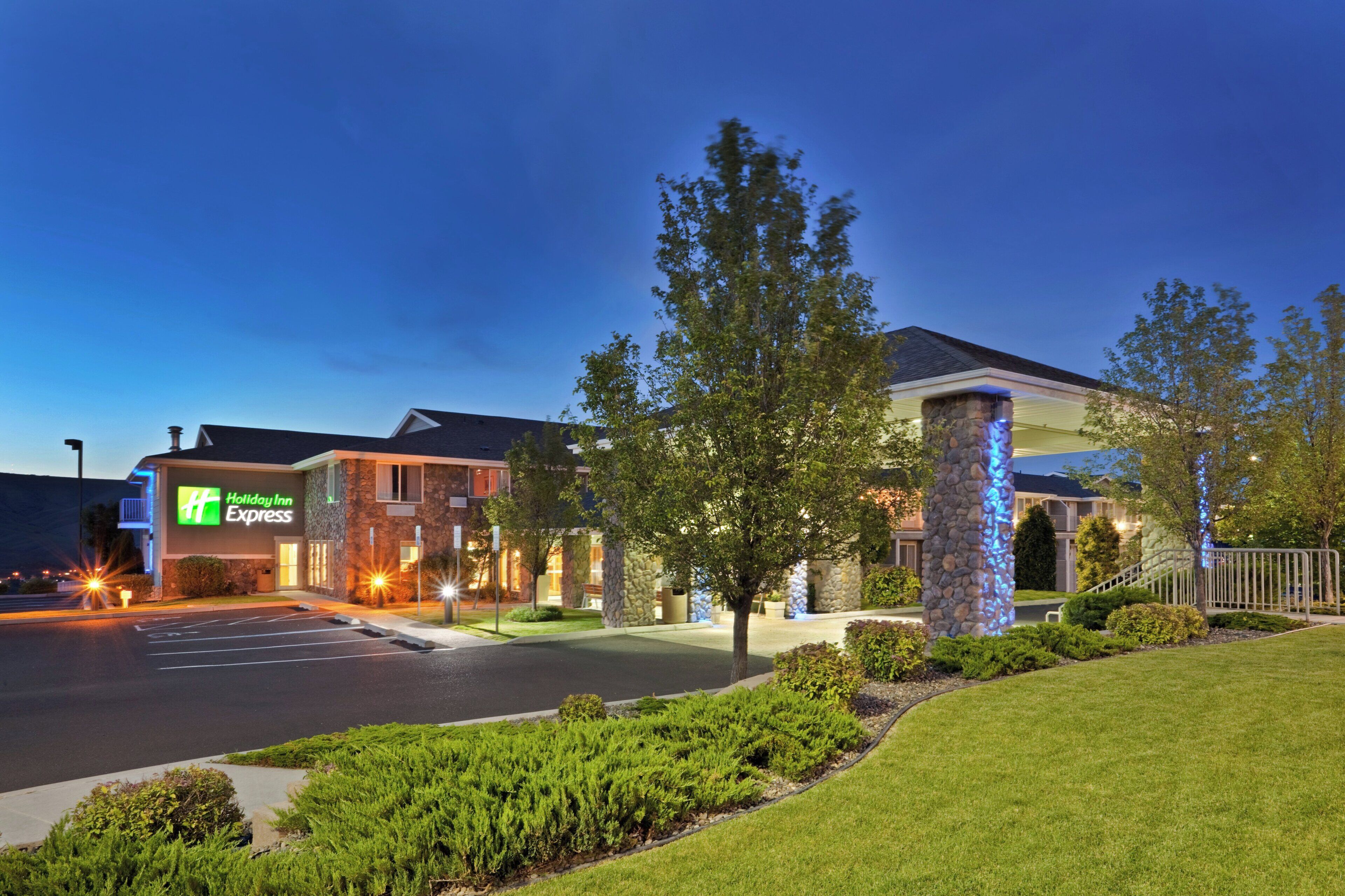 Un hôtel Holiday Inn Express doté d’une façade en pierre, d’un parking et d’une pelouse bien entretenue.