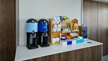 A coffee station with two coffee dispensers, a hot water dispenser, and a variety of coffee pods and creamer boxes.