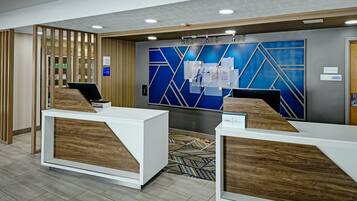 A reception area with two white reception desks, a blue geometric wall design, and a wooden panel wall.
