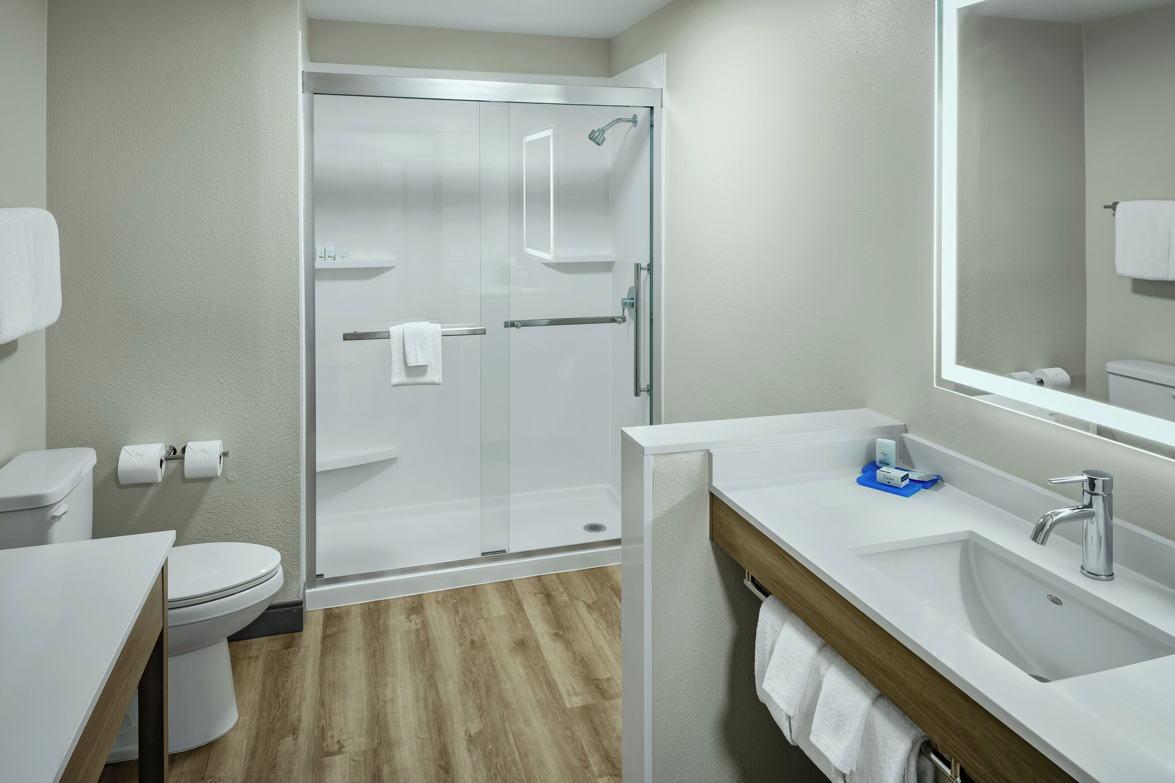 Un baño moderno con cabina de ducha de vidrio, un lavamanos blanco y un inodoro.