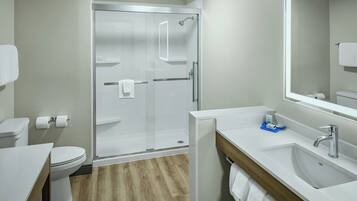 Un baño moderno con cabina de ducha de vidrio, un lavamanos blanco y un inodoro.