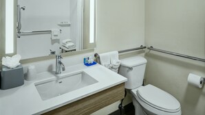 A modern bathroom with a white sink, mirror, and toilet.