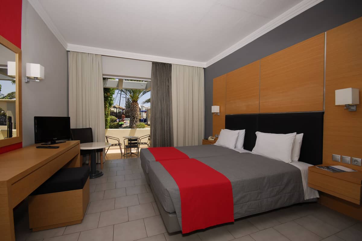 A hotel room with a bed, desk, chair, and a view of the outdoors.