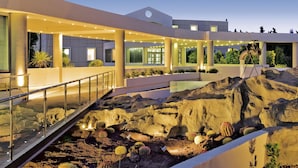 Un bâtiment moderne doté d’une allée couverte, d’un jardin de rocaille et d’un espace piscine.