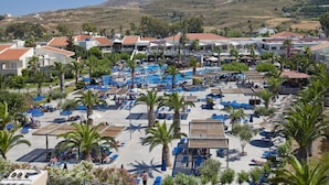 Un complexe hôtelier doté de plusieurs piscines, de palmiers et offrant une vue sur un paysage montagneux.